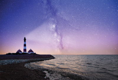 Unter dem Sternenhimmel mit einem Leuchtturm